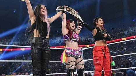 Iyo Sky (M.) feierte ihren großen Sieg mit den Partnerinnen Dakota Kai (l.) und Bayley