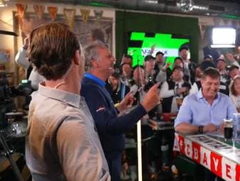 Die SPORT1-Experten Thomas Strunz und Peter Neururer werden im Fantalk von einem Männerchor empfangen.