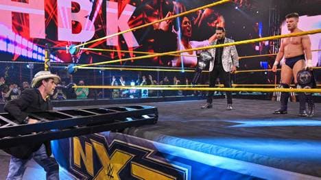 WWE-Legende Shawn Michaels überrascht Santos Escobar (links im Ring) & Jordan Devlin mit einer Leiter