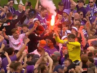 Der VfL Osnabrück ist nach dem Sieg gegen SV Wehen Wiesbaden Meister der 3. Liga und feiert den Aufstieg. Nach Abpfiff stürmen Fans den Platz und feiern ausgelassen mit der Mannschaft.