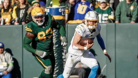 Los Angeles Chargers quarterback Justin Herbert (R) scrambles away from Green Bay Packers defensive tackle T.J. Slaton (L) during the NFL, American Football Herren, USA game between the Los Angeles Chargers and the Green Bay Packers at Lambeau Field on Sunday, November 19, 2023. PUBLICATIONxINxGERxSUIxAUTxHUNxONLY GBW20231119816 TANNENxMAURY