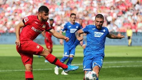 LEVERKUSEN, GERMANY - AUGUST 31: Kevin Volland of Bayer 04 Leverkusen shoots past Konstantinos Stafylidis of TSG 1899 Hoffenheim during the Bundesliga match between Bayer 04 Leverkusen and TSG 1899 Hoffenheim at BayArena on August 31, 2019 in Leverkusen, Germany. (Photo by Christof Koepsel/Bongarts/Getty Images)