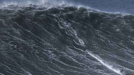 Ein Surfer in den Wellen vor Nazare