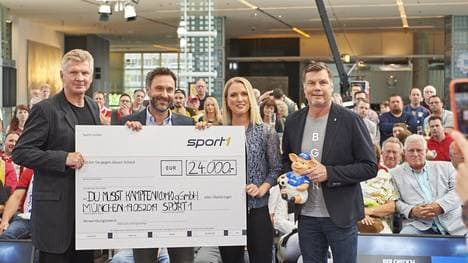 SPORT1-Experte Stefan Effenberg, Jan Schauhuber, Geschäftsführer CHECK24 Vergleichsportal für Versicherungen GmbH, sowie die SPORT1-Moderatoren Ruth Hoffmann und Thomas Helmer (v.l.) präsentieren den Spendenscheck