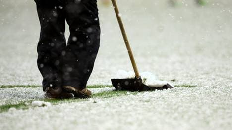 Ein Fußballplatz wird vom Schnee befreit