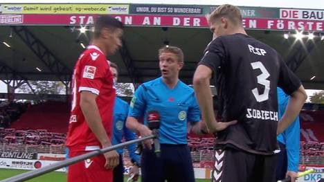 Schiedsrichter Robert Schröder trifft Spieler mit Münze