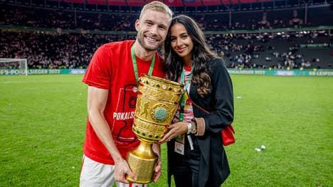 Leipzigs Konrad Laimer und seine Frau Ines-Sarah präsentieren die Trophäe nach dem DFB-Pokalfinale 2022