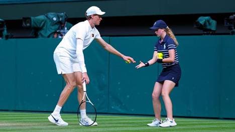 Jannik Sinner gibt den Korken an ein Ballmädchen weiter