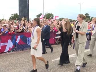 Englands Europameisterinnen landen nach ihrem Triumph in London und werden von einer begeisterten Menge empfangen.