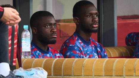 Dayot Upamecano (l.) neben Tanguy Nianzou auf der Ersatzbank des FC Bayern München