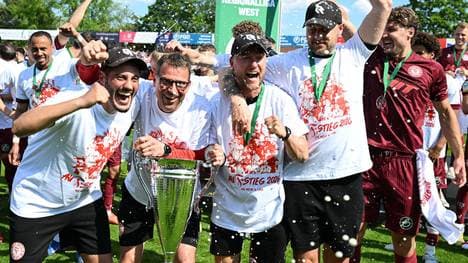 Fortuna Kölns Trainerteam um Chefcoach Matthias Mink (zweiter von links) feiert die Rückkehr in den Profifußball