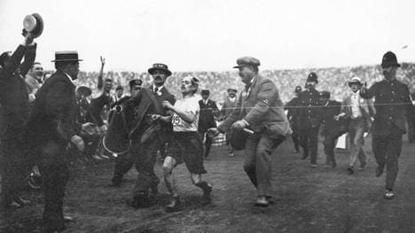 Dorando Pietri wird beim Olympia-Marathon 1908 von Helfern gestützt und schleppt sich als Erster ins Ziel - wird aber disqualifiziert