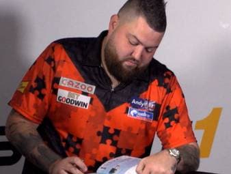 Michael Smith schreibt ins SPORT1-Freundschaftsbuch - und ist bei seinen Hunden deutlich hin- und hergerissen. Gleich zweimal tauchen sie auf, genauso wie seine Kids. Die Darts-WM ab dem 15. Dezember auf SPORT1.
