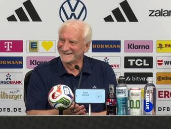 Ein US-Reporter versucht, Rudi Völler eine Frage auf Deutsch zu stellen. Sein Versuch ist zwar alles andere als optimal, doch von Rudi Völler und den anwesenden Kollegen gibt es Applaus.