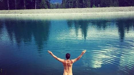 Felix Neureuther zieht vor einem Bergsee blank